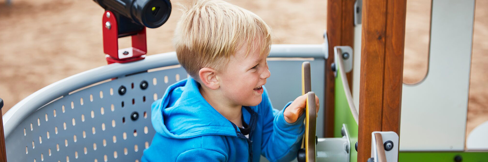 A boy smiles as he turns the ships wheel on a UniMini Structure